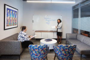 room-with-couch-2-chairs-white-board-and-two-women